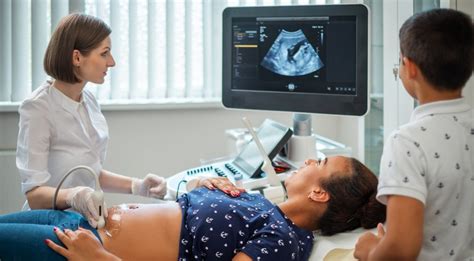 Besilaukianti moteris su partneriu, žiūrintys į ultragarso nuotrauką