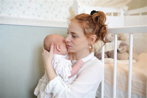 Moteris, besilaukianti kūdikio, sėdi konsultacinėje patalpoje