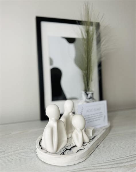 Simbolinė moters ir vaiko figūrėlės, apsuptos rankų