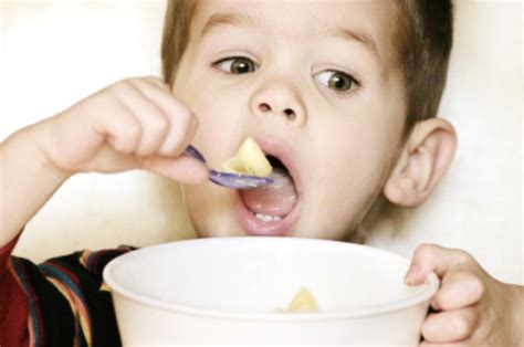 Kūdikis valgo košę iš buteliuko su šaukšteliu