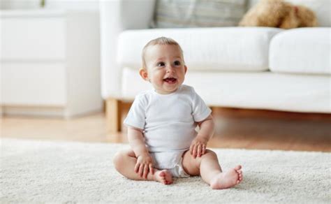 Kūdikis sėdi ant kilimėlio