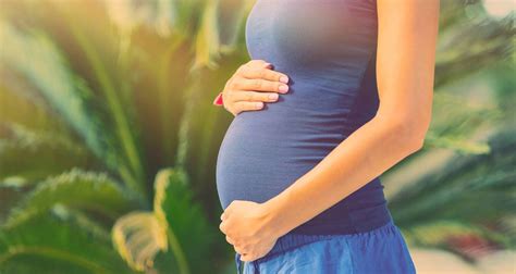 Nėščios moters rankos, švelniai laikantis pilvą