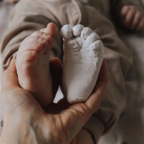 Motinos ir tėvo rankos, laikančios kūdikio pėdutę