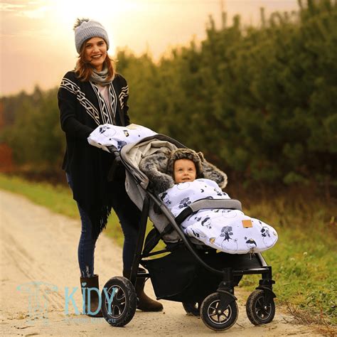 tėvai deda kūdikį į vežimėlį su miegmaišiu