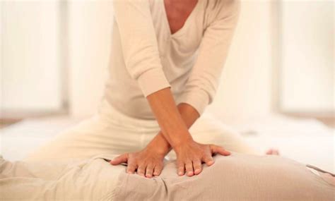 Persona che esegue un massaggio Shiatsu su un materassino a terra