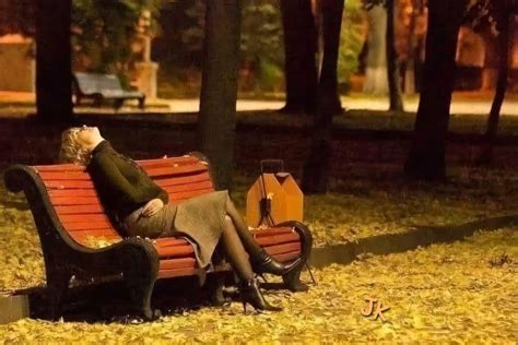 Moteris sėdi viena ant suoliuko parke, atrodanti liūdna