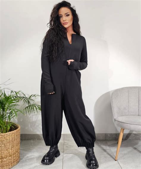 Juodas blizgučių kombinezonas su asimetrine iškirpte ir ilgomis rankovėmis